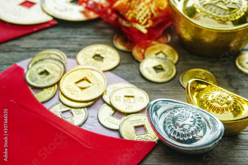 Close up  coins spread out from red envelope decorate with gold bar on the wood table , chinese new year decotation concept. photo