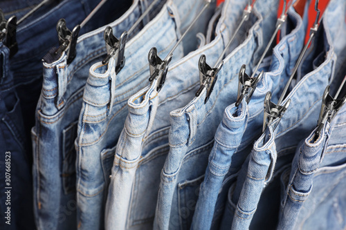 Metal hangers with different stylish jeans, closeup