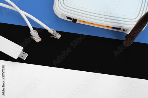 Estonia flag depicted on table with internet rj45 cable, wireless usb wifi adapter and router. Internet connection concept photo