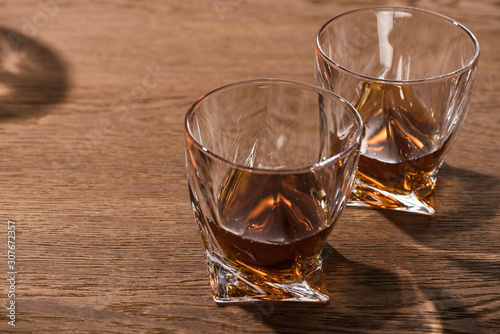 Two glasses of brandy with shadow on wooden table