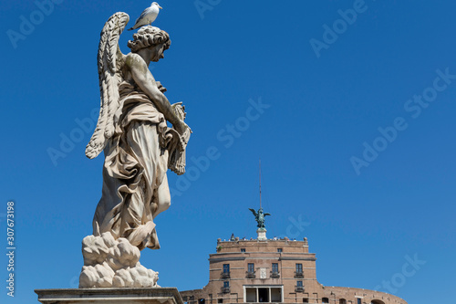 Wallpaper Mural Statue on the pont Sant'Angelo or bridge of Angels in rome against a blue sky with a seagull and the Castle of Angles or Castel d'Angleo in the background Torontodigital.ca