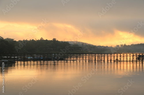 A wooden bridge with mountain landscape over the river at Sunrise in Thailand. © karita