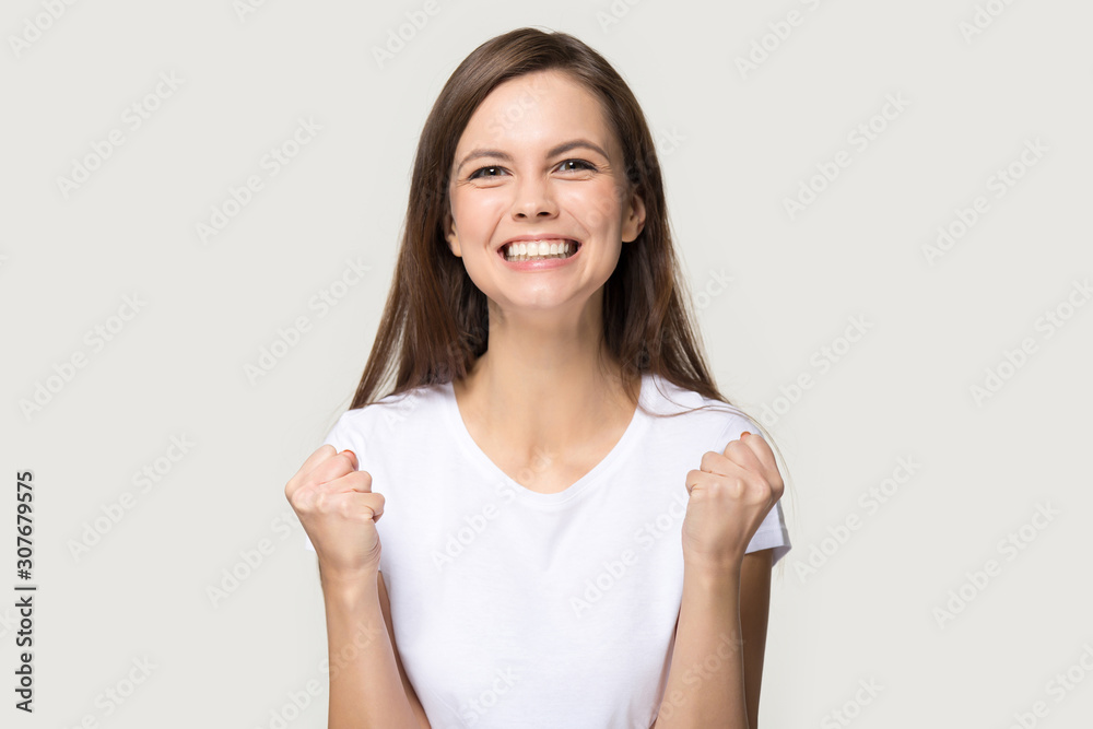 Excited young woman clench fists as sign of victory Excited young woman clench fists as sign of victory