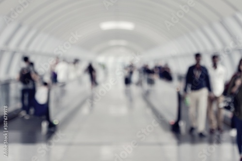 Blurred image of people and passengers keep baggage walking in airport going to terminal hall , boarding gate in airport on a modern walkway for background usage. travelling or business concept