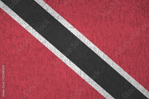 Trinidad and Tobago flag depicted in bright paint colors on old relief plastering wall. Textured banner on rough background © mehaniq41