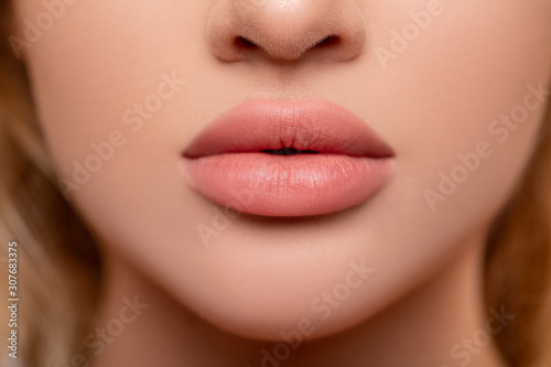 Beautiful lips Close-up. Makeup. Lip matte lipstick. Sexy lips. Part of face, young woman close up. advertisement. perfect plump lips bodily lipstick. peach color of lipstick on large lips.  photo
