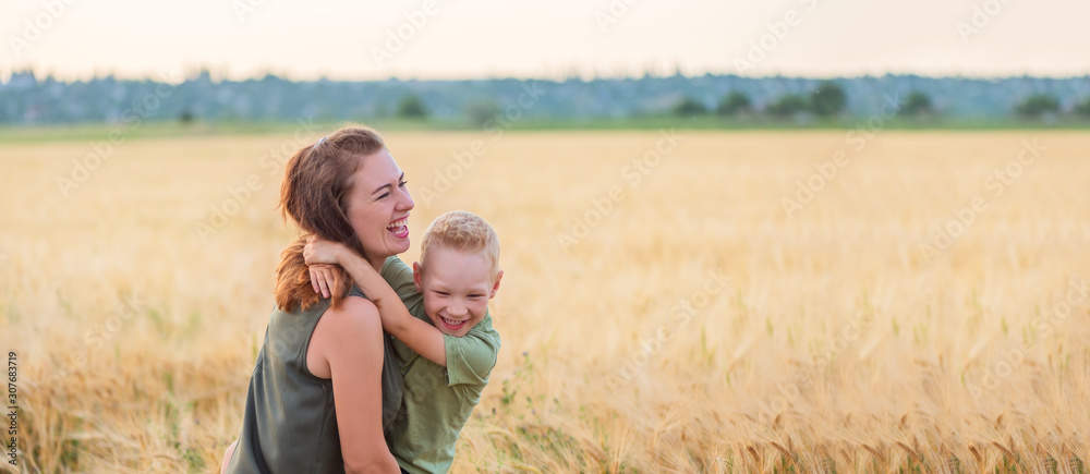 Mother and son hugging and laughing in a wheat field at sunset Mother and son hugging and laughing in a wheat field at sunset
