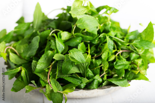 Mint. Bunch of Fresh green organic mint leaf in bowl on wooden table closeup  