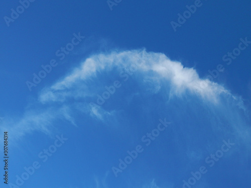 In the dark blue sky a white cloud in the form of an arc