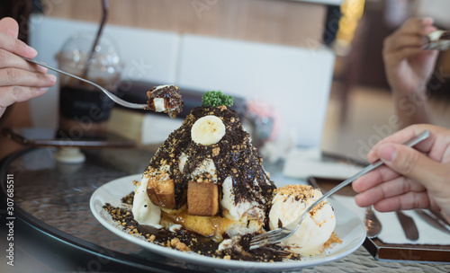 Selective focus ice cream cake with enjoying family eat honey banoffee toast menu in white dish on table at restaurant.Eating party concept. photo