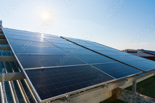 Solar panels and blue sky with light flare background.Solar cells farm on the roof.Photovoltaic modules for renewable energy.Save the earth and the energy with good environment concept.