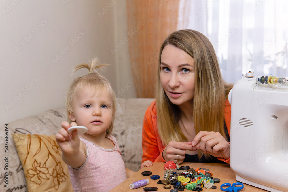 Fototapeta premium mother communicates with her little daughter, sorting through buttons