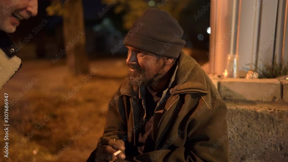 Passerby talking to homeless man on the sidewalk at night. Passerby talking to homeless man on the sidewalk at night.