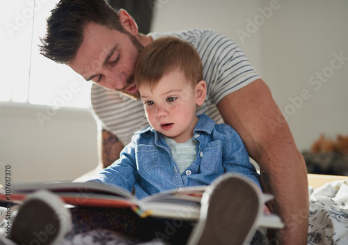 Adorable, young female toddler learning to read book with handso