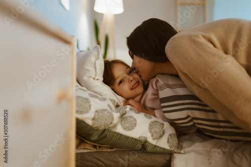 mom kisses daughter on the cheek before going to bed