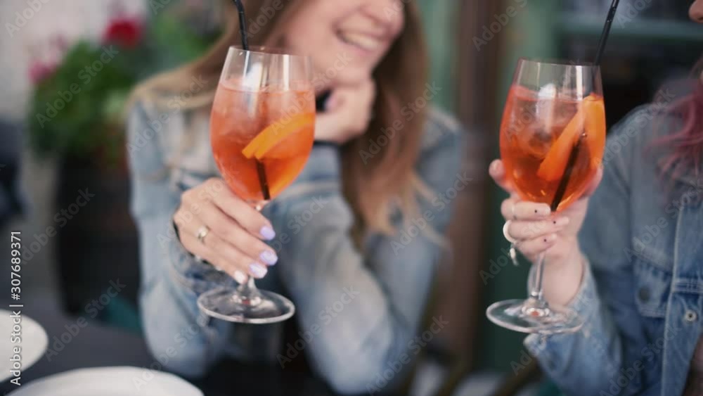 Two friends drink cocktail in a street European cafe, the concept of female friendship and joint recreation Two friends drink cocktail in a street European cafe, the concept of female friendship and joint recreation