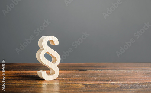 A wooden paragraph figurine. Democratic institutions, human rights and property. Legislation and lawmaking. Justice and judicial system concept. Legal assistance, services of lawyers.