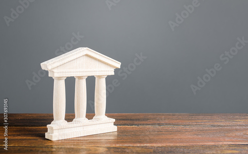 White building figurine with pillars in antique style. Concept of city administration, bank, university, court or library. Architectural monument in old town part . Banking, education, government. photo