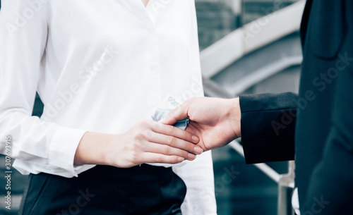 Businessman and businesswoman making handshake with money in hands. Bribery and corruption concepts