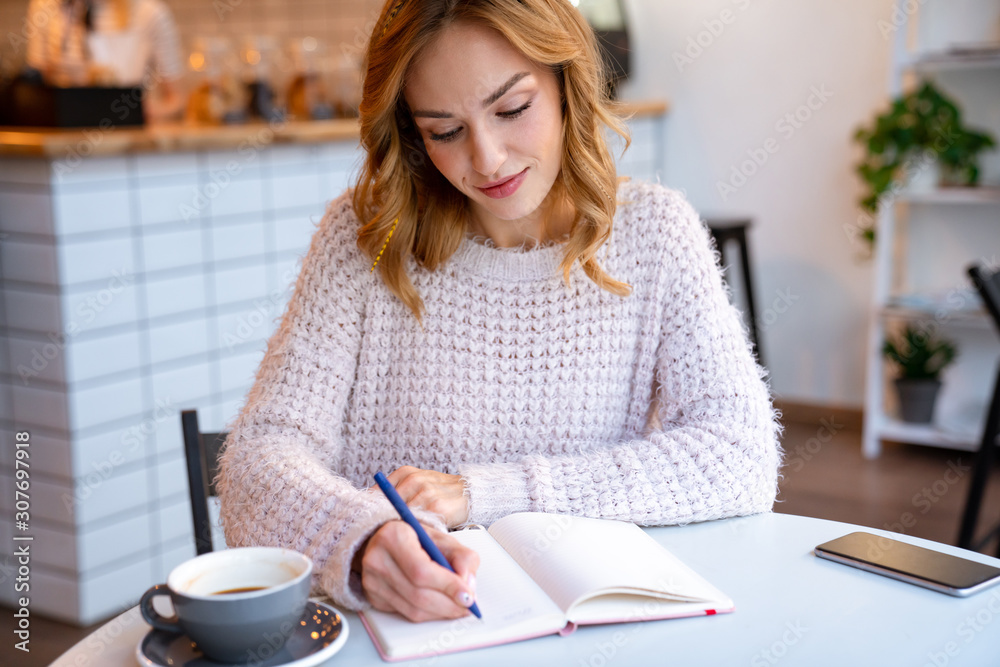 Concentrated pretty young blonde woman writing notes Concentrated pretty young blonde woman writing notes