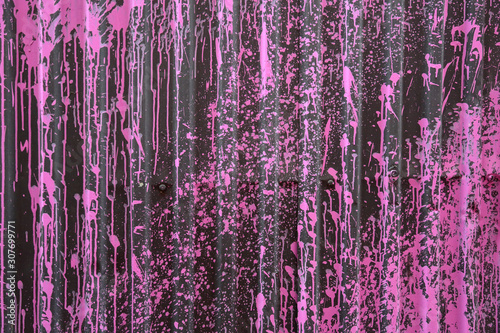 Textured metal surface with pink spots of paint