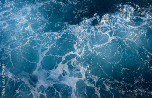 Photo of a stormy sea with foam. Blue surface as background.