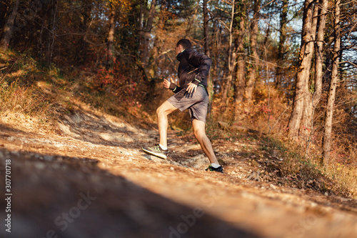 The concept of sport and healthy lifestyle. A young slender man in sports clothes is engaged in running uphill in the autumn forest or Park. Rear view