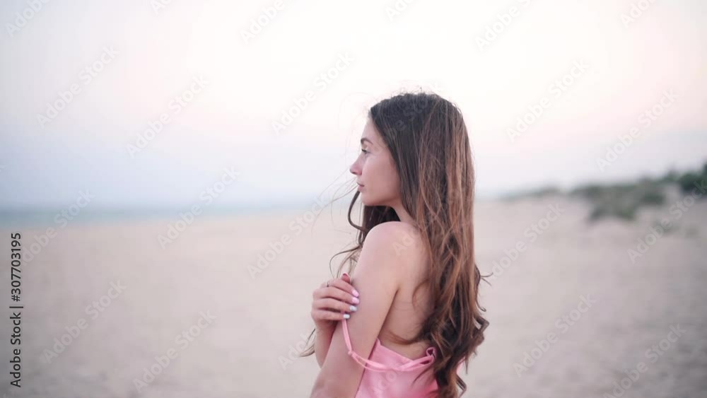 Young pretty girl with long bunette hair and blue eyes staying with denuded shoulder against the sea Young pretty girl with long bunette hair and blue eyes staying with denuded shoulder against the sea
