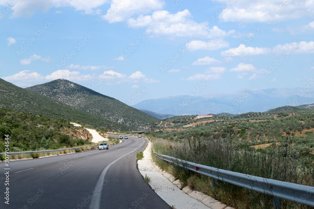 Driving on the picturesque greek road on Peloponnese surrounded by mountain landscape under blue sky