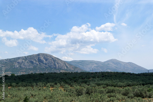 Greek landscape with mountains olive trees and clouds