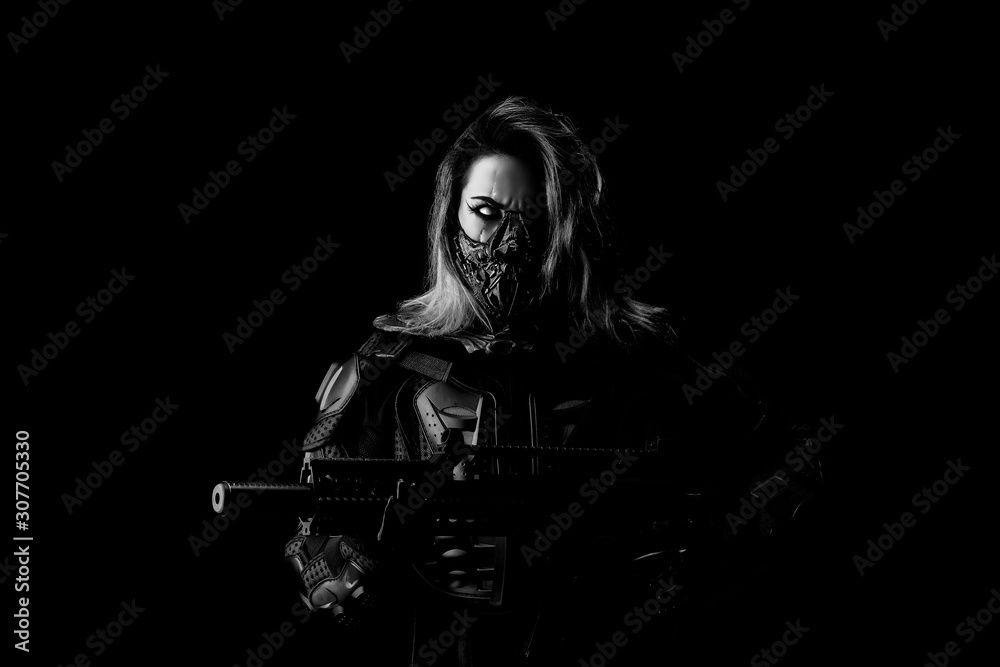 Young one-eyed Cyborg, wearing a mask, in combat armor, holding a machine gun in his hand Young one-eyed Cyborg, wearing a mask, in combat armor, holding a machine gun in his hand