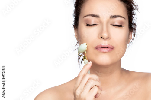 Fotografie Beautiful model woman with healthy fresh clean skin using a jade roller