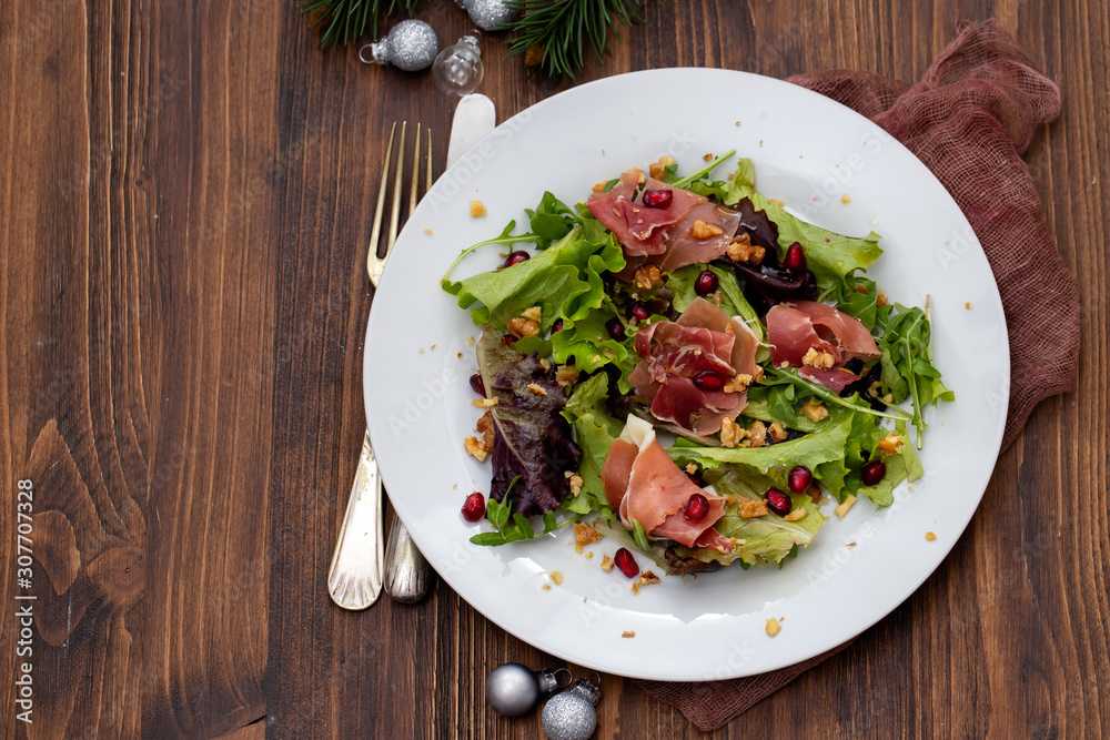 salad prosciutto with pomegranate on white plate