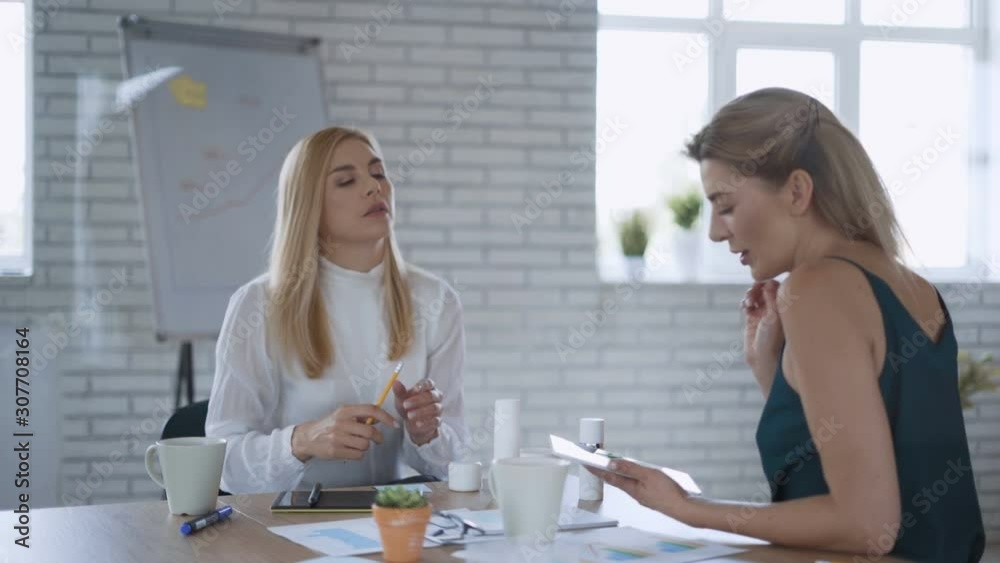Two blonde women are testing cosmetics for sale at the office. care cosmetics concept 4K
