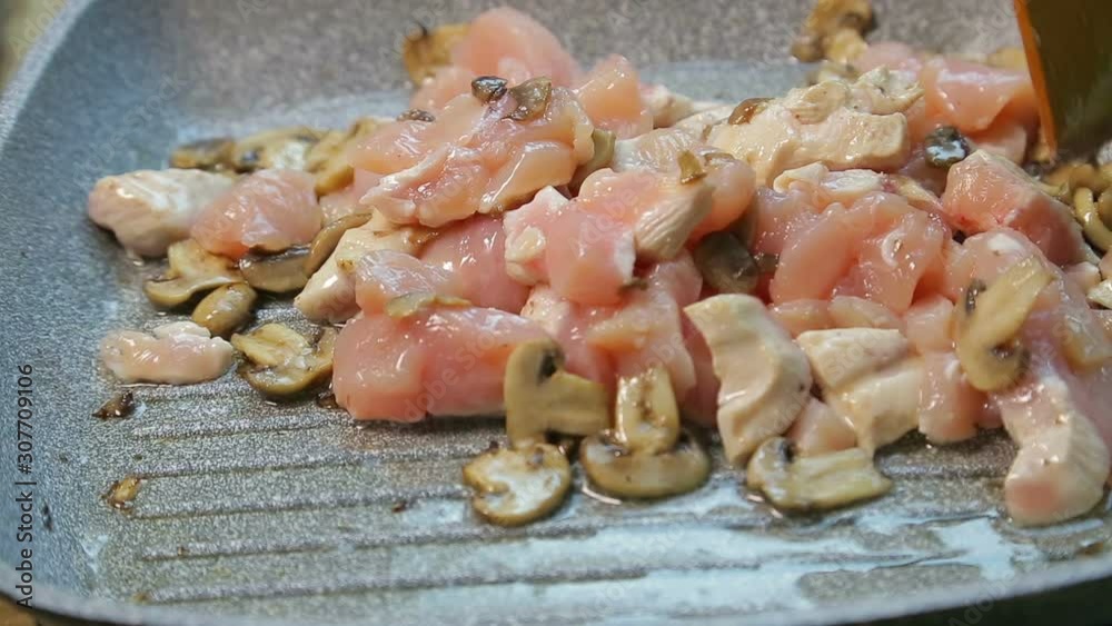 Chicken fillet in oil is mixed in a pan with a wooden spatula Chicken fillet in oil is mixed in a pan with a wooden spatula