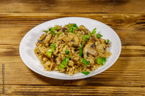 Tasty risotto with mushrooms on wooden table