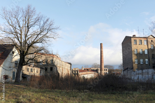 Abandoned factory outdoors at sunny autumn day with brown brick walls and chimney against blue sky background