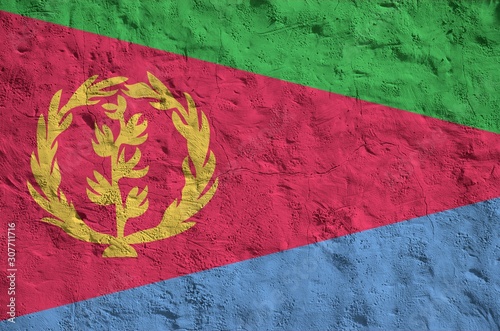 Eritrea flag depicted in bright paint colors on old relief plastering wall. Textured banner on rough background photo