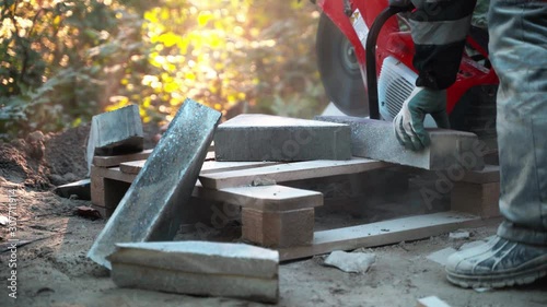 Wallpaper Mural Concrete cutting machine. A worker in the park area cuts heavy slabs for a walkway in the park. Works concrete cutting in the park during the day. A lot of dust scatters. Worker takes cut slabs and Torontodigital.ca