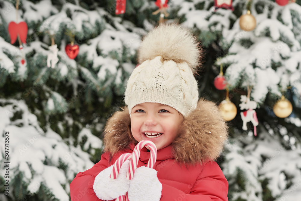 Girl in winter forest. Funny baby laughing outdoors in winter day. .Happy winter girl in park snow. Christmas in winter forest or park. .Christmas baby on Christmas tree background. Child with candy.. Girl in winter forest. Funny baby laughing outdoors in winter day. .Happy winter girl in park snow. Christmas in winter forest or park. .Christmas baby on Christmas tree background. Child with candy..