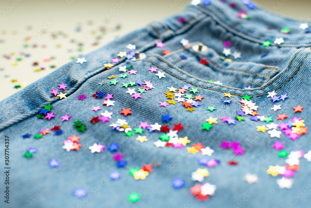 Festive colorful confetti scattered at light blue jeans. Close up of jeans  decoration tiny shining stars. Mom denim pants at ivory background. Modern  fashion. Stock Photo | Adobe Stock
