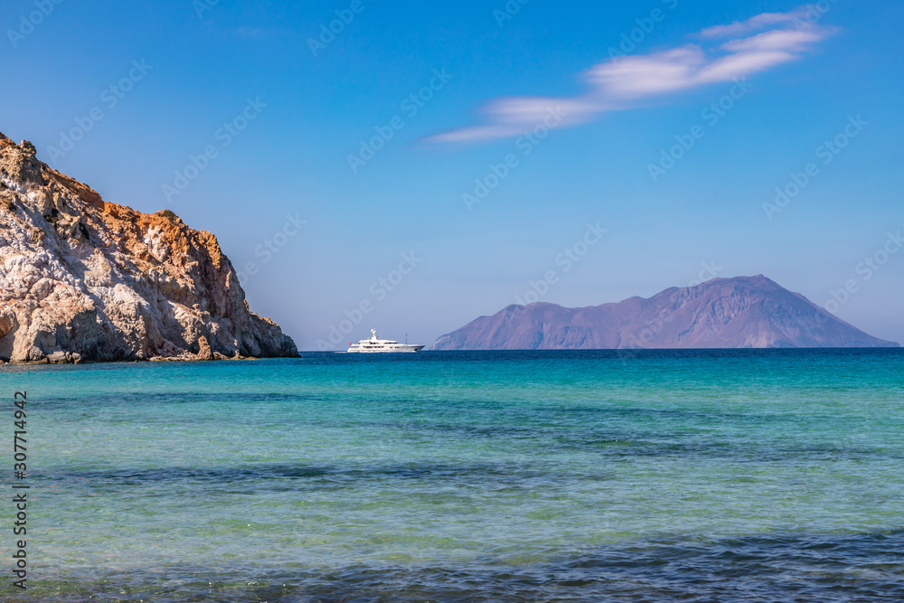 Plathiena beach with cliffs, island and a Yacht