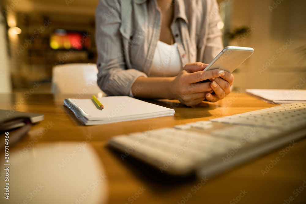 Close-up of woman text messaging on smart phone at home.