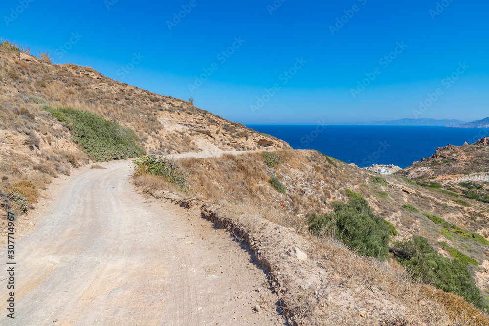 Road to Firopotamos beach with church, houses and cliffs Road to Firopotamos beach with church, houses and cliffs