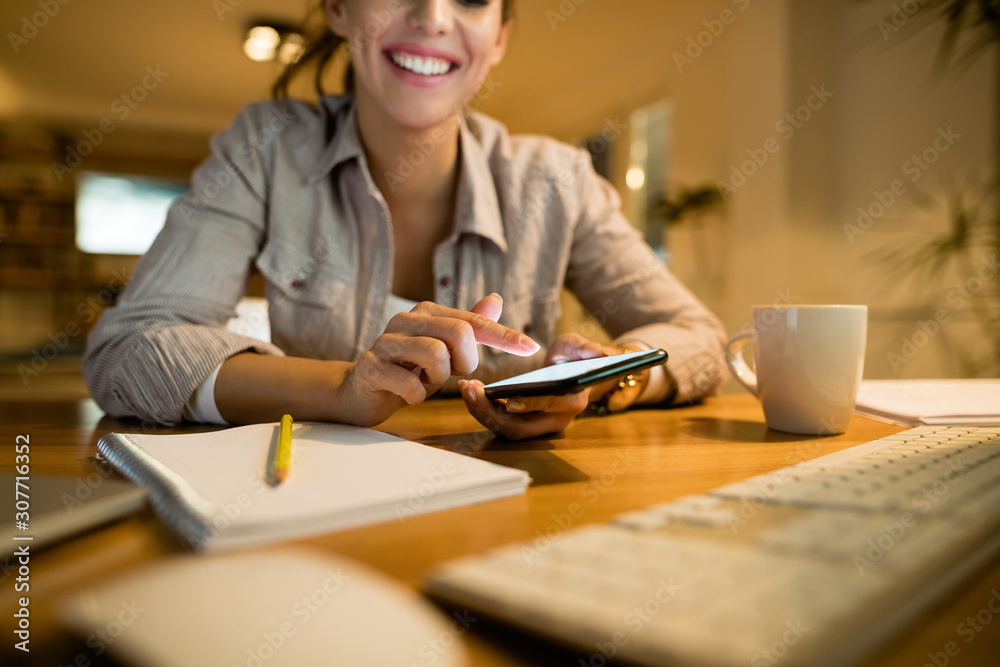 Close-up of happy woman using mobile phone in the evening at home.
