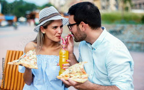 Couple eating pizza outdoors. Dating  consumerism  food  lifestyle concept