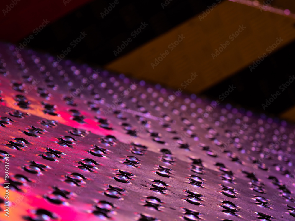 Fototapeta premium Close up of the ribbed non slip steel floor plates, reflecting different colours.