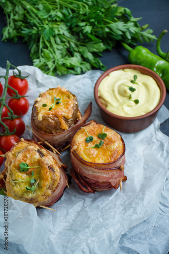 Baked young potatoes with cheese, bacon. Dark background. Close-up. Space for text.