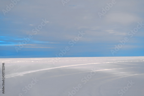 Path under a turquoise sky through a snowy field. The horizon between the sky and the snow field divides the frame in a ratio of one to four. You can place the text top.