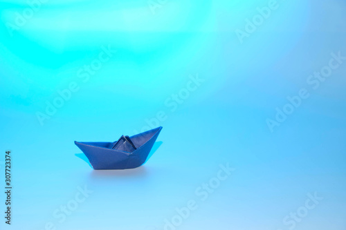 Paper blue ship in an imaginary sea of Cyan Blue Color. Copy Space.